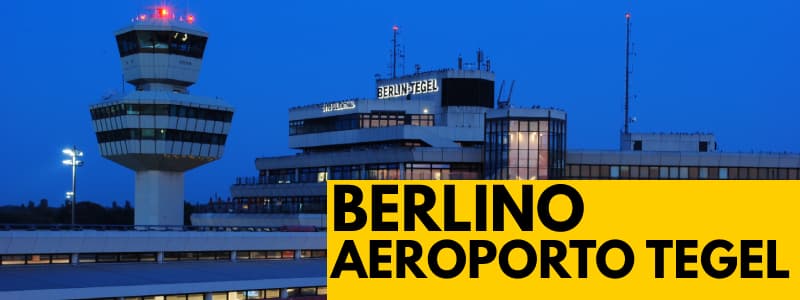 Fotografia di notte dell'esterno dell'aeroporto di Berlino Tegel con rettangolo giallo in basso a destra con scritta nera "Berlino Aeroporto Tegel"