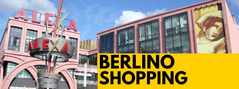 Fotografia dell'esterno del centro commerciale ALEXA di Berlino in una giornata limpida con rettangolo giallo in basso a destra con scritta nera Berlino Shopping